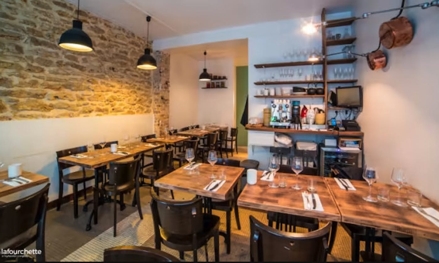 La salle du Mijo T : pierres apparentes, tables en bois brut, casseroles en cuivre au mur